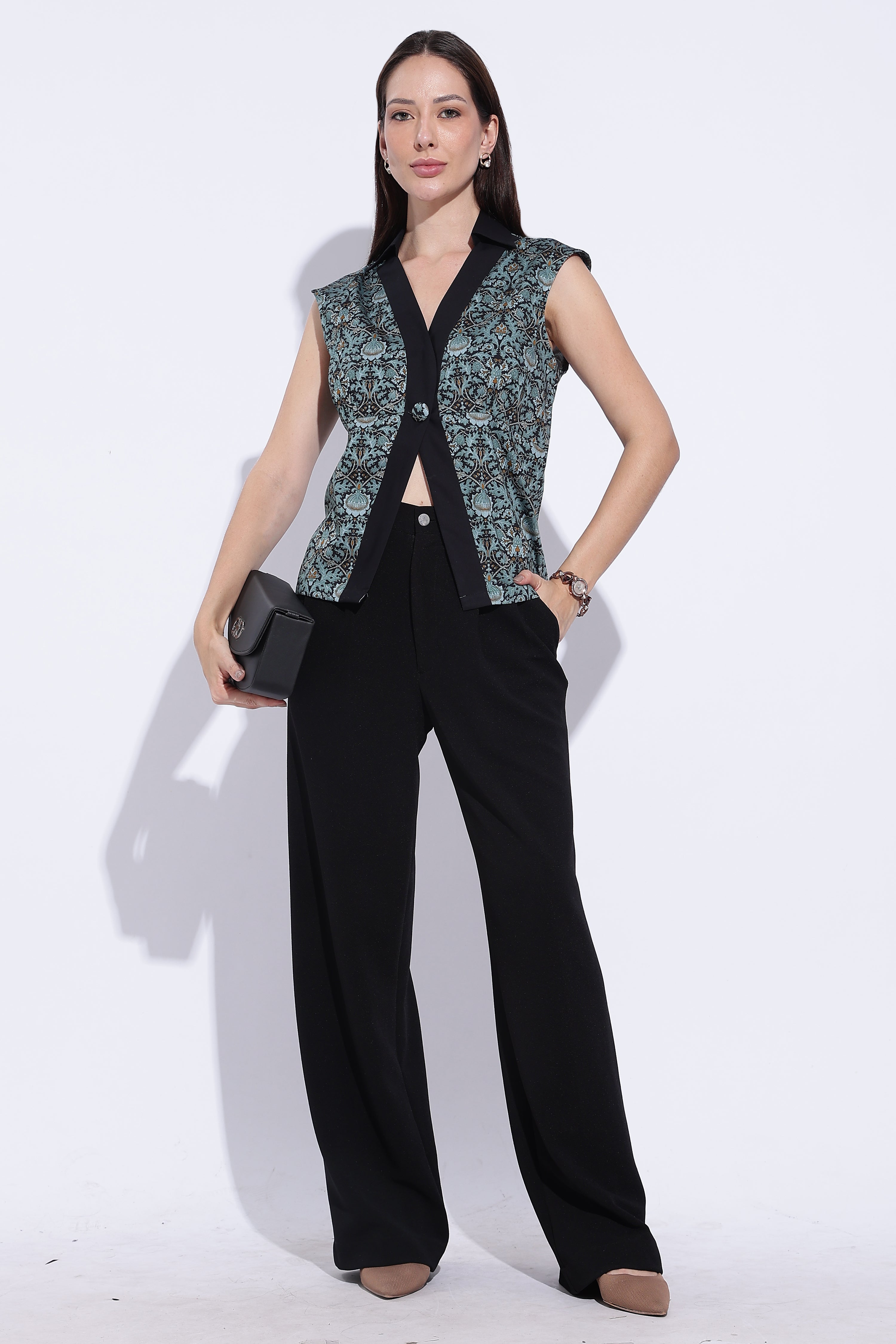 Woman wearing a black outfit with a patterned vest on a white background
