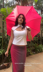 Woman holding a red umbrella outdoors with greenery in the background